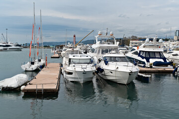Obraz premium Sailboats and yachts docked at a marina under overcast skies near a coastal city - Sochi, Russia April 14, 2023