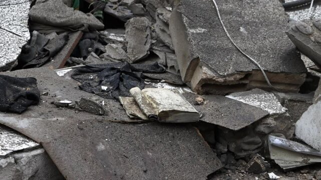A torn, dusty book lies abandoned among rubble and debris, symbolizing loss and devastation in the aftermath of disaster or conflict. Loss, destruction, forgotten history, resilience after a disaster