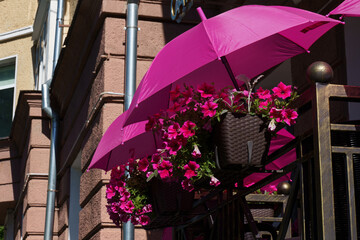 Bright pink umbrellas enhance a charming balcony filled with vibrant flowers