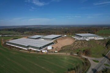 Solar panels installed on a roof of a large industrial building or a warehouse. Modern Industrial buildings in the background. Horizontal photo.Aerial panorama landscape of solar powerplant on roof	
