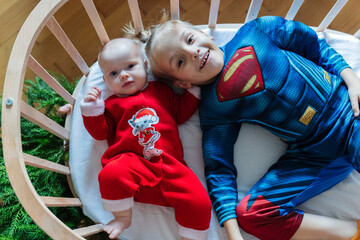 Baby and boy in superhero and Christmas costumes