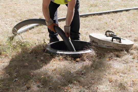 Worker pumping septic tank. Septic tank pumping service