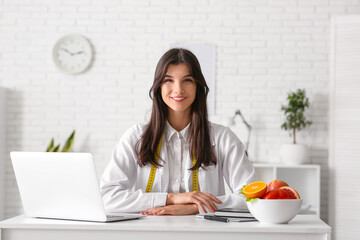 Female nutritionist sitting at table in office