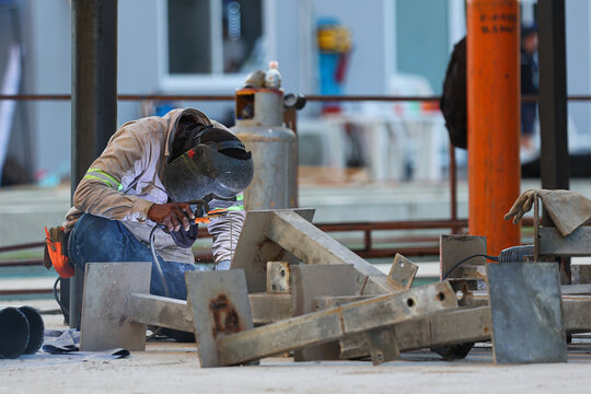 latin blacksmith welding metal structure at construction site