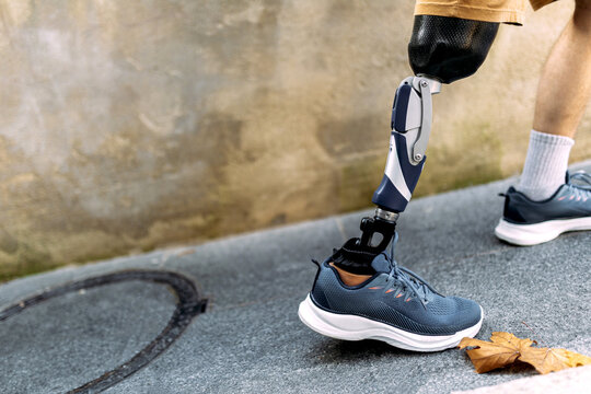 Man with modern prosthetic leg walking outdoors on sidewalk