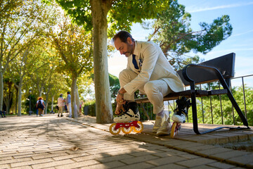 Man tying roller skates on park bench outdoors
