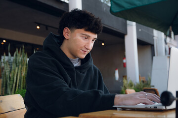 Happy young man with vitiligo checking his social media in a restaurant with a laptop