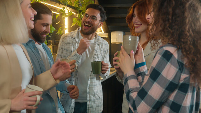 Happy multiracial group friends team mates freelance co-workers students colleagues joyful business men women diverse girls guys dancing male female buddies drink coffee dance laugh office break party