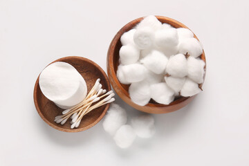 Wooden bowls with cotton balls, pads and swabs on white background
