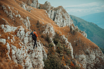 A male climber climbing up on the mountain rock cliff, adventure travel, adrenaline extreme sport outdoor.