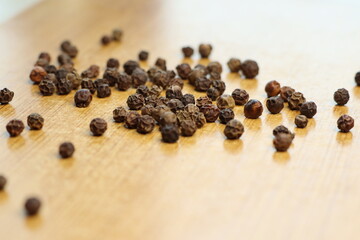A detailed closeup shot showcasing Black Peppercorns beautifully arranged on a Wooden Surface