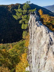 The vertical cliff with sharp edge drops into the fall colored forest at the summit of Seneca...