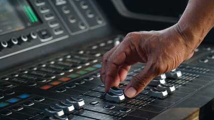 Audio sound mixer with focus to the man's hand moving the slider