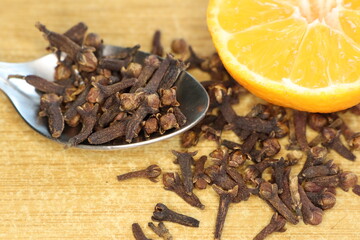 Obraz premium A visually appealing arrangement of cloves and an orange slice displayed on a rustic wooden surface