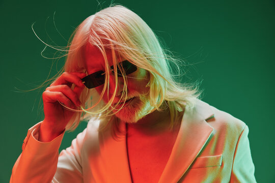 Stylish elderly man with sunglasses against an abstract green and red background, showcasing confidence and modern fashion trends Ideal for concepts of aging, fashion, and self expression