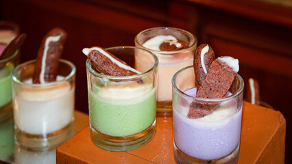 A vibrant display of neatly arranged puddings in green, white, and pink, each topped with a crispy...