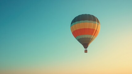 Fototapeta premium A colorful hot air balloon floats against a blue sky with a golden sunset in the background.