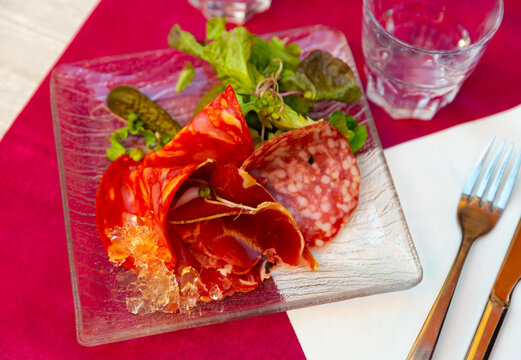 Delicious smoked assorted meat of dried sausage and sliced carbonade, served with pickled gherkins and lettuce leaves