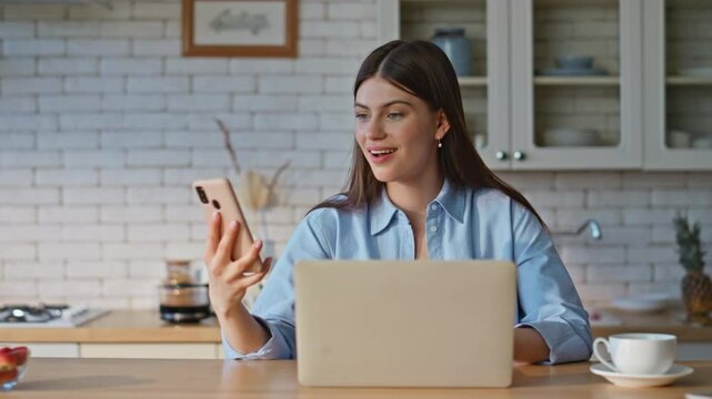 Woman winner checking smartphone notification at computer table remote closeup