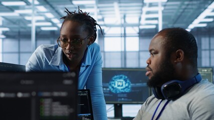 Engineer working with colleague on computer in high tech data center establishment monitoring...