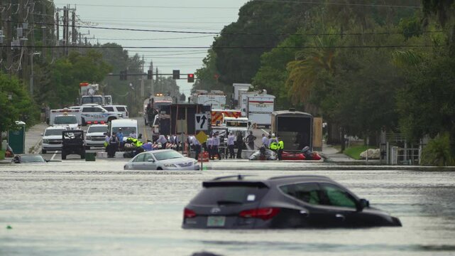 Rescue workers on flooded road. Emergency response in Florida residential area. Consequences of hurricane Debby natural disaster