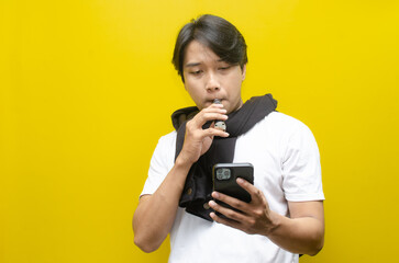 Young Asian Man Holding E-Cigarette Amidst Thick Clouds of Vapor