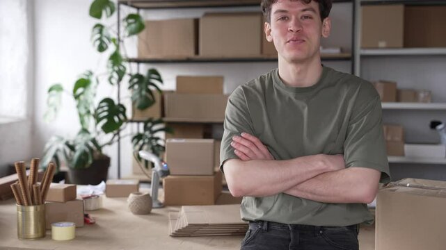 A blond young startup businessman smiles and looks at the camera. Warehouse, workshop, packaging and shipping of the product