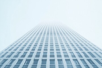 Fototapeta premium Reaching for the Sky: A minimalist perspective of a towering skyscraper, its uniform facade reaching towards a hazy sky. The image evokes ambition and architectural grandeur. 