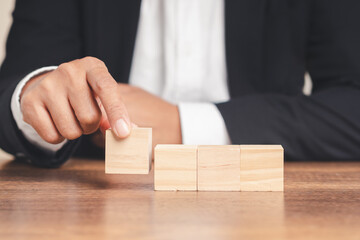 Businessman arranging wooden blocks on desk.