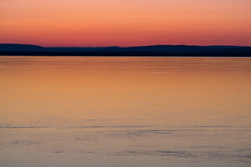 Obraz premium Calm Water at Sunset with Distant Hills