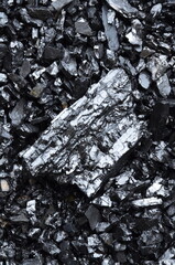 A large piece of anthracite coal lies on top of a seed grade anthracite.