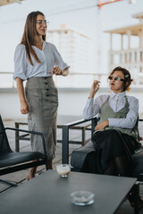 Obraz premium Two multicultural business workers take a relaxing break on the office terrace. They are enjoying coffee and engaging in a friendly conversation, exemplifying a professional yet laid-back atmosphere.