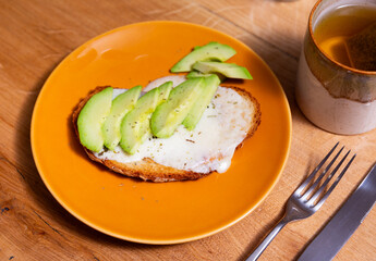Toast with sliced avocado and cheese served on plate