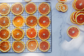orange slices in preparation to make decorative dried oranges on dehydrator rack.