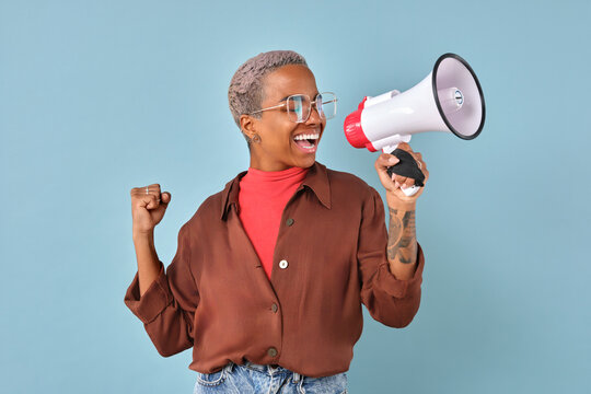 Enthusiastic individual joyfully raises a megaphone, showcasing confidence and energy. The backdrop is a lively blue, enhancing the positive vibes of this dynamic moment.