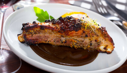 Baked pork ribs baked under mustard sauce served at plate with spiced sauce....