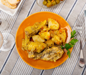 Tasty baked chicken drumsticks and potatoes at plate closeup