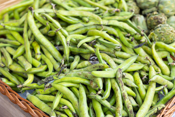 Bunch of fresh green peas lies on counter in vegetable shop..