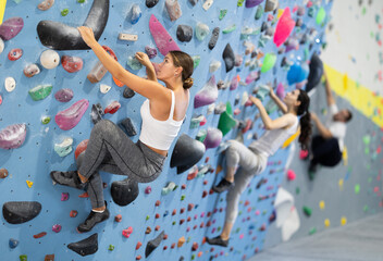 Young woman in sportswear practicing rock climbing on climbing wall