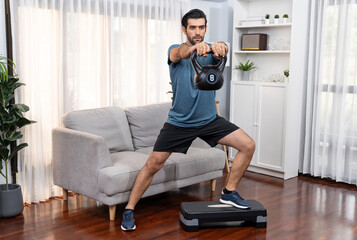 Fototapeta premium Athletic body and active sporty man doing squat with kettlebell weight for effective targeting muscle gain at gaiety home as concept of healthy fit body home workout lifestyle.
