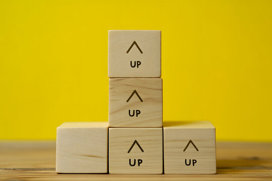 A hand stacking wooden blocks with the word �gUP�h written on them.