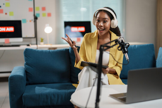 woman in yellow blazer hosting podcast with headphones and microphone in modern studio