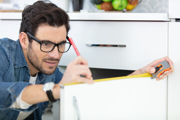 young repairman installing induction cooker in kitchen