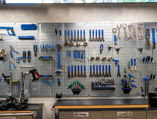 Pegboard with various tools hanging in bicycle repair shop