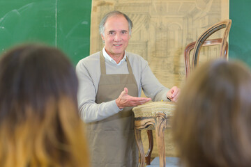 senior craftman showing how to fix an old chair