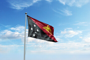Waving flag of Papua New Guinea in blue sky. Papua New Guinea flag for Republic Day and...