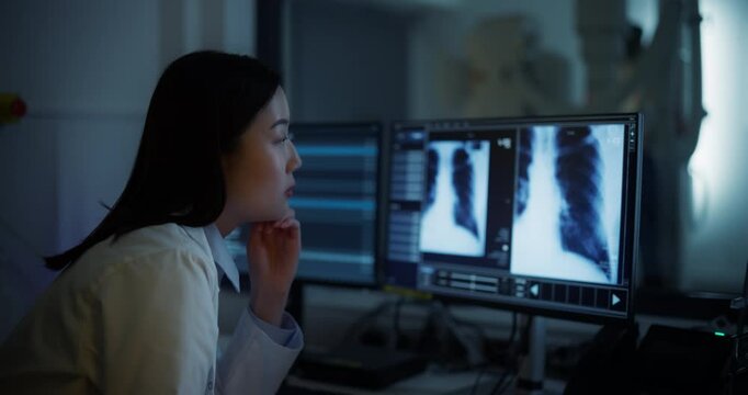 Asian Female Doctor Inspecting X-ray Scans on an Advanced Diagnostic Application in a Hospital in a Radiology Medical Office. Radiographer Working on a Computer, Looking at Medical Images