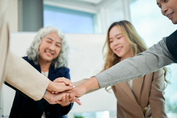 Fototapeta premium A close-up of businesspeople's hands coming together in a teamwork gesture, celebrating success.