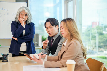 Diverse Asian businesspeople working together in a modern office, all focused on the discussion.