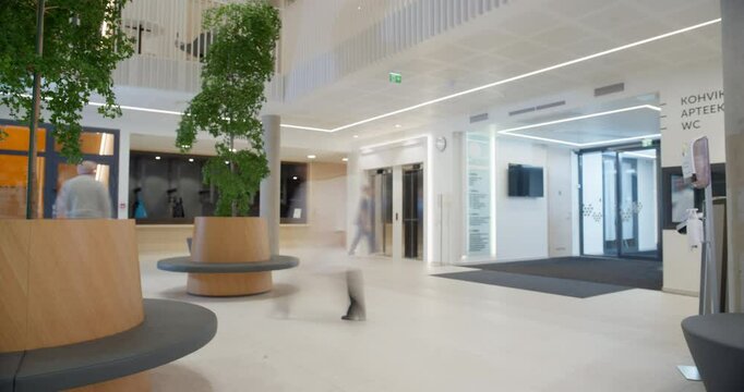 Timelapse of Modern Hospital Lobby with a Busy Flow of Patients, Visitors, and Staff. Doctors, Nurses and Specialists Working in Clinic. Female and Male Healthcare Officials Walking in a Hall